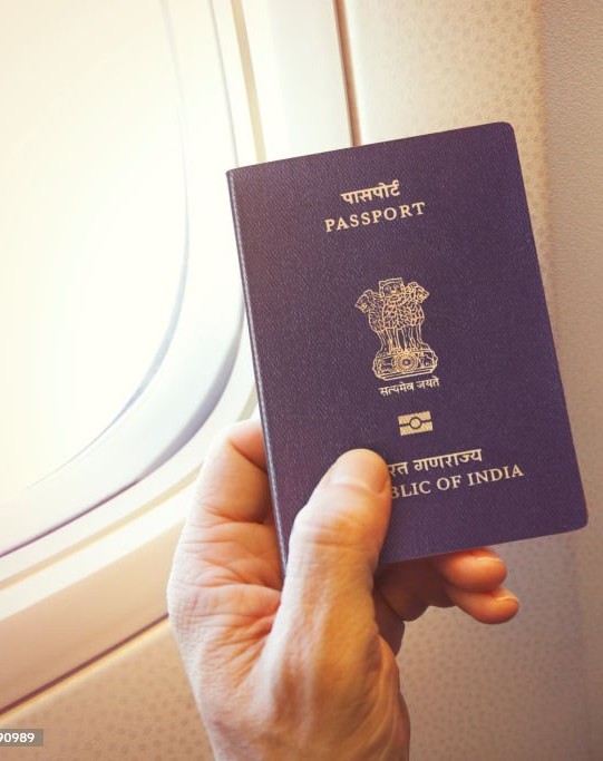 Detail of passenger's hand holding Indian passport on the airplane